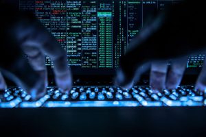 26 April 2019, Hessen, Rüsselsheim: LLUSTRATION - A man is typing on the illuminated keyboard of a laptop, a hacker program is open on the screen. Photo: Silas Stein/